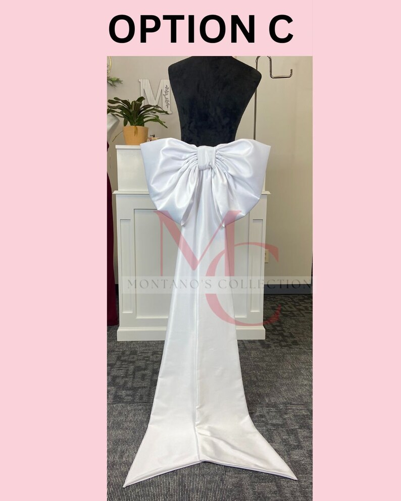 May include: White satin chair sash with a large, white bow. The sash is tied around the back of the chair and has a long, flowing tail.