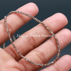 May include: A strand of brown diamond beads, strung together to form a necklace. The beads are small and have a rough, faceted texture.