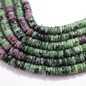 Può includere: Una collana di perline di pietre preziose verdi e rosa. Le perline sono rotonde e hanno un motivo maculato.