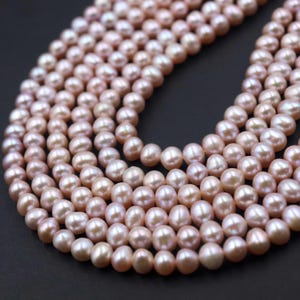 Peut inclure: Gros plan de plusieurs rangées de perles d'eau douce roses. Les perles sont rondes et ont un éclat brillant. Le fond est noir uni, ce qui fait ressortir les perles.