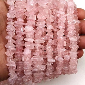 May include: A strand of pink rose quartz chip beads. The beads are irregular in shape and have a natural, polished finish.