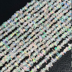 Peut inclure: Un brin de perles en opale blanche irisée. Les perles sont de forme irrégulière et ont un aspect naturel et brut.