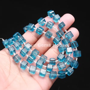 Puede incluir: Una hebra de cuentas de piedras preciosas azules, cada cuenta es de forma cuadrada con bordes facetados. Las cuentas están enhebradas en un alambre de plata.