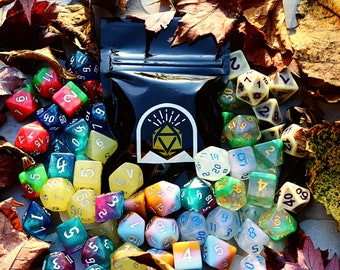 May include: A collection of colorful dice with various numbers and symbols. The dice are scattered on a surface with fall leaves and a black pouch with a gold logo.
