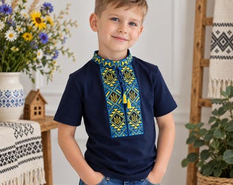 May include: A navy blue short-sleeved shirt featuring a central vertical panel with intricate yellow and light blue geometric embroidery and the Ukrainian trident symbol. The collar has matching embroidery and two yellow tassels on thin cords.