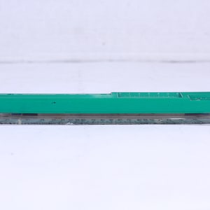 Puede incluir: Una regla de plástico verde con un transportador de plástico transparente unido a ella. La regla está marcada en pulgadas y el transportador está marcado en grados.