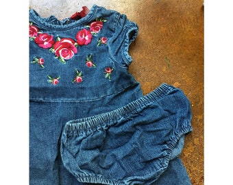 May include: A denim dress with a floral embroidery design and a matching denim diaper cover.