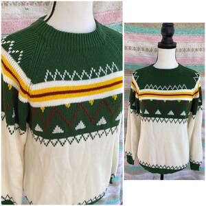 May include: A green and white knit sweater with a geometric pattern. The sweater has a crew neck and long sleeves.