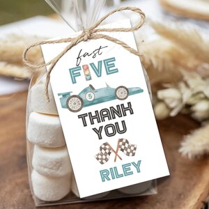 May include: A cellophane bag filled with marshmallows, tied with twine and a tag. The tag has a light blue race car graphic and the words "fast FIVE THANK YOU RILEY" in black and teal lettering.