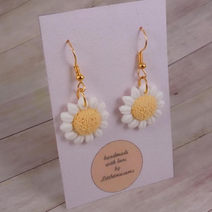 Könnte beinhalten: Ein Paar goldene Ohrhänger mit weißen und gelben Gänseblümchen-Anhängern. Die Ohrringe sind handgefertigt mit Liebe von Littletreasures.
