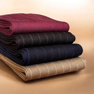 May include: A stack of four folded knit socks featuring a fine pinstripe pattern. The colours from top to bottom are burgundy with dark stripes, black with white stripes, navy blue with blue stripes, and tan with white vertical pinstripes.