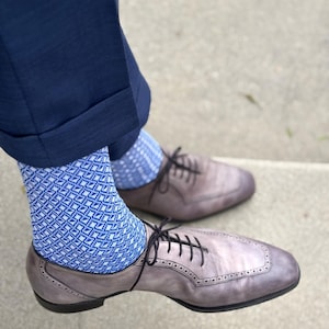 Puede incluir: Un par de zapatos de cordones de cuero gris con un diseño de brogue. Los zapatos se llevan con calcetines de patrón azul.