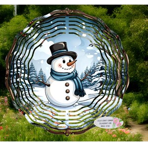 May include: A round, multi-layered metal wind spinner with a snowman design. The snowman is wearing a black top hat and a blue scarf. The background is a winter scene with snow-covered trees. The wind spinner is surrounded by green foliage.