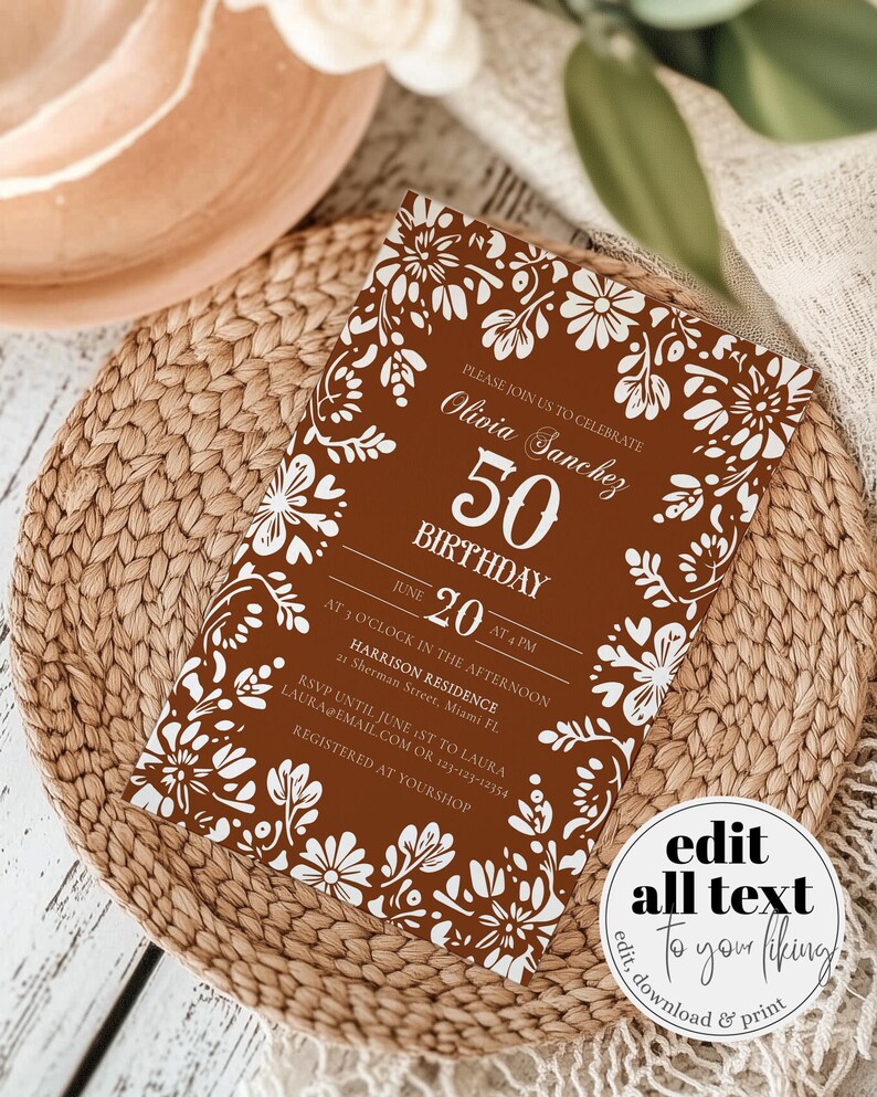 Peut inclure: Une invitation d'anniversaire marron avec des motifs floraux blancs et du texte. L'invitation indique "Olivia Sanchez 50e anniversaire le 20 juin &agrave; 16h". L'invitation est sur un tapis tress&eacute;.