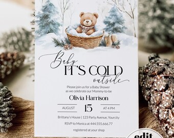 May include: A rectangular baby shower invitation card featuring a watercolor illustration of a brown teddy bear in a wicker basket amidst snowy blue pine trees. The text reads Baby IT'S COLD outside, Olivia Harrison, August 15 at 4 PM, and event details.