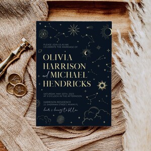 May include: A navy blue wedding invitation with gold foil accents. The invitation features a celestial design with stars, moons, and planets. The text reads "Please join us as we celebrate the marriage of Olivia Harrison and Michael Hendricks. Saturday, May 20th, 2023 at 3 o'clock in the afternoon. Harrison Residence, 21 Sherman Street, Miami FL. Dinner & dancing to follow."
