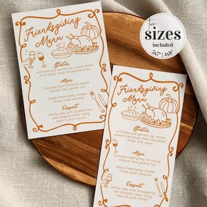 Peut inclure: Deux cartes de menu Friendsgiving avec une bordure et du texte orange. Les menus comprennent une entrée, un plat principal et un dessert. Les cartes sont sur un plateau de service en bois. Une étiquette indique deux tailles : 12,7x17,8 et 10,2x20,3 cm.