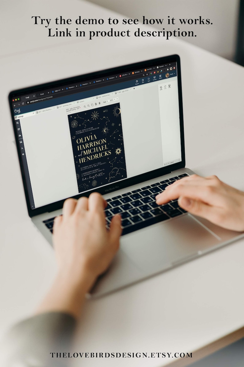 May include: A laptop computer displaying a wedding invitation with a dark blue background and gold stars, moons, and clouds. The invitation text reads "Please join us as we celebrate the marriage of Olivia Harrison and Michael Hendricks".