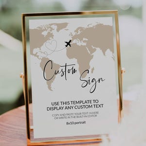 May include: A gold-framed sign featuring a world map design and the words "Custom Sign" in cursive. A heart and airplane graphic are above the text. The sign is 20.3 x 25.4 cm and includes instructions for custom text.