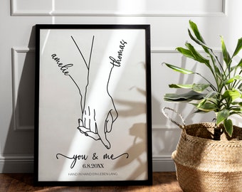 May include: Black and white line art print of two hands holding each other. The names "amelie" and "thomas" are written in cursive along the arms. The text "you & me 6.8.20XX HAND IN HAND EIN LEBEN LANG." is printed below the hands.