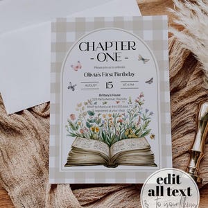 May include: A printable invitation for a first birthday party with a book and floral theme. The invitation features a white and brown gingham background with a large open book with flowers and butterflies. The text on the invitation reads "Chapter One - Olivia's First Birthday - August 15 at 4 PM".