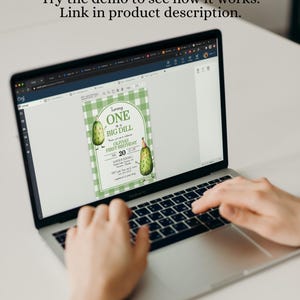 Op de afbeelding: Een laptop toont een verjaardagsuitnodiging met een groen en wit ruitpatroon. De uitnodiging luidt "Turning ONE Big Dill" met een cartoon augurk illustratie. De tekst "Try the demo to see how it works. Link in product description." staat bovenaan.