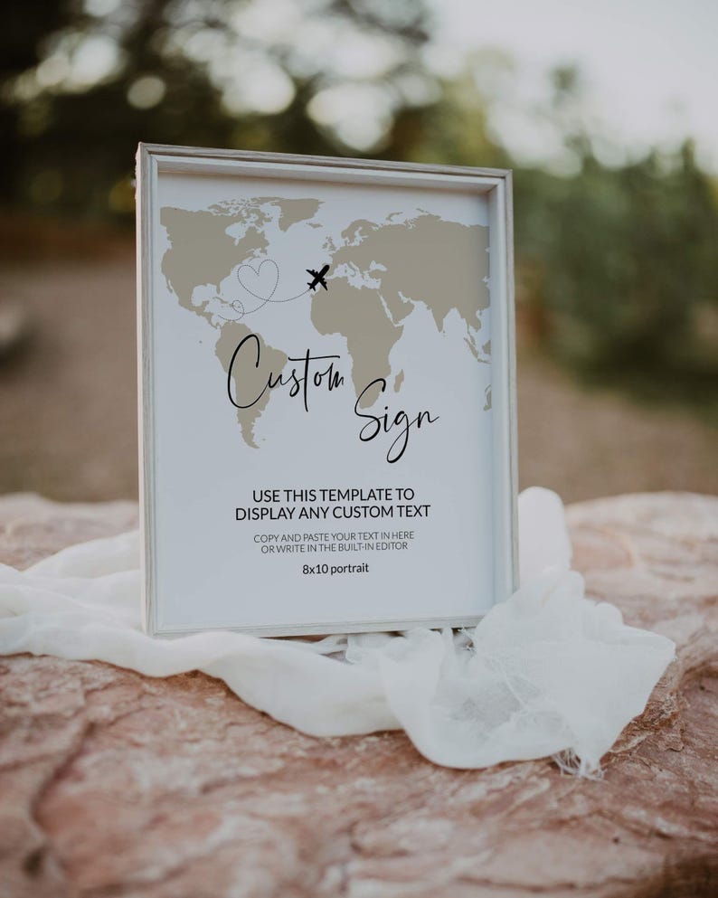 May include: A framed sign featuring a world map design, an airplane graphic, and the words "Custom Sign." The sign is 20.3 x 25.4 cm and includes instructions for adding custom text. The frame is silver.