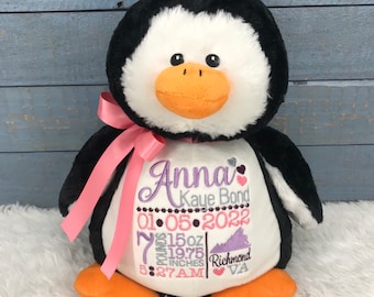 May include: A plush penguin toy with black and white fur, an orange beak, and orange feet. A pink ribbon is tied around its neck. The white belly features embroidered text: Anna Kaye Bond, 01-05-2022, 7 pounds 15oz, 19.75 inches, 5:27AM, Richmond VA.