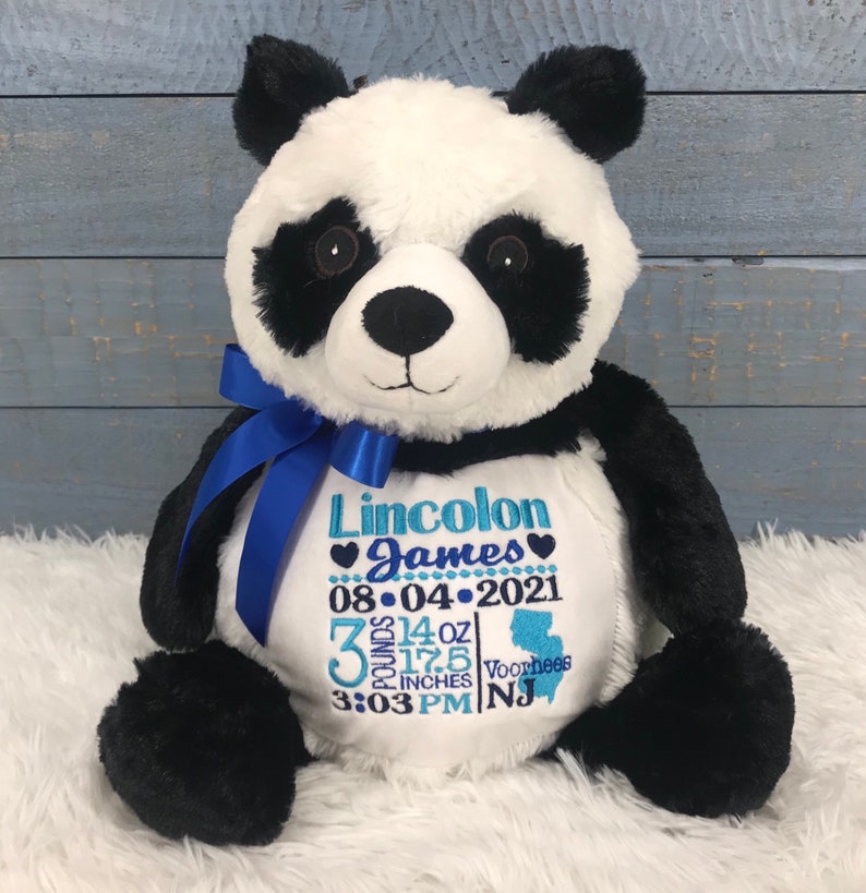 Może przedstawiać: Pluszowa panda z czarno-białym futerkiem, przewiązana niebieską satynową wstążką na szyi. Na białym brzuszku znajduje się niebieski haft z tekstem: Lincolon James, 08-04-2021, 3 pounds 14 oz, 17.5 inches, 3:03 PM oraz Voorhees NJ.