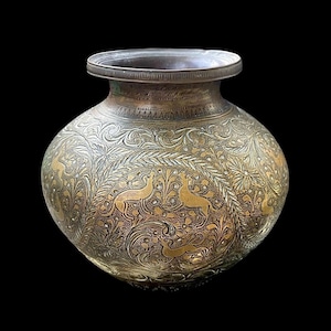 May include: A bronze-coloured, round pot with intricate floral and deer engravings. The pot has a wide, slightly flared rim and a bulbous body. The detailed carvings create a textured surface.