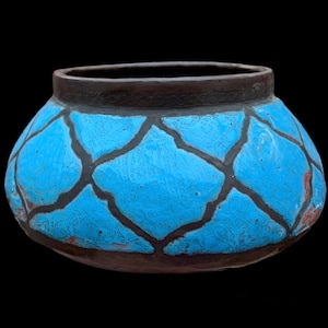 May include: A blue and brown ceramic pot with a geometric design. The pot has a wide base and a narrow opening.