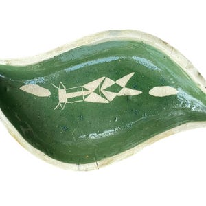 Peut inclure: Plat en céramique vert en forme de feuille avec un motif géométrique blanc. Le plat a une finition texturée et brillante et un bord crème. Le motif semble être peint à la main.