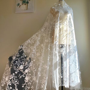 May include: White lace fabric with a floral pattern. The lace is delicate and has a soft, flowing texture.
