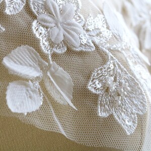 May include: White lace fabric with floral embroidery and sequins. The fabric has a delicate, feminine look and would be perfect for a wedding dress or other special occasion garment.