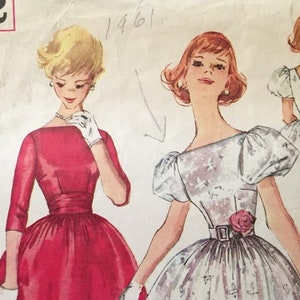 May include: Vintage sewing pattern for a dress with a full skirt and puffed sleeves. The pattern is for a teen size 12 with a bust measurement of 32 inches. The pattern is printed on a white background with a black border. The pattern is dated 1961.