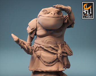 Op de afbeelding: Een 3D-geprint miniatuur van een kikkerachtig wezen dat een harnas draagt en een staf vasthoudt. Het wezen heeft een groot hoofd met een brede mond en een klein lichaam. Het miniatuur is in lichtbruin geverfd. Het miniatuur is getiteld "The Shellback Ritual".