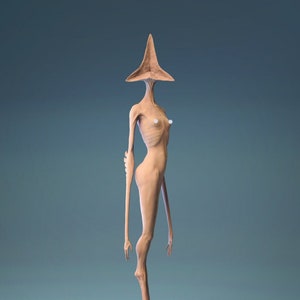 Puede incluir: Una figurita de color beige de una figura humanoide con una cabeza triangular y extremidades largas y delgadas. La figura está de pie sobre una base circular con una superficie texturizada.