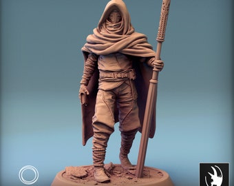 May include: A miniature figurine of a hooded figure wearing a cloak and holding a staff. The figure is painted in a brown colour and is standing on a base. The figure is part of the "People of Dunnari" collection.