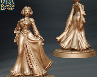 Pode incluir: Uma miniatura dourada de uma mulher vestindo um longo vestido fluido com detalhes intrincados. A miniatura está em pé sobre uma base circular.