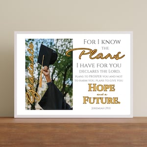 May include: A white card with a gold border and a photo of a person wearing a black graduation cap and gown. The text on the card reads "For I know the plans I have for you declares the Lord, plans to prosper you and not to harm you, plans to give you hope and a future. Jeremiah 29:11"