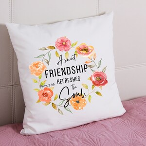 May include: White throw pillow with a floral wreath design and the text "A sweet FRIENDSHIP REFRESHES the Soul. Prov. 27:9"