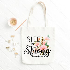 May include: White canvas tote bag with a floral design and the text "SHE is Strong Proverbs 31:25"