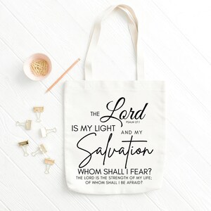 Op de afbeelding: Witte canvas tote bag met zwarte tekst die luidt: "The Lord is my light and my Salvation. Psalm 27:1. Whom shall I fear? The Lord is the strength of my life; of whom shall I be afraid?"