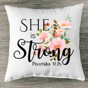 May include: White throw pillow with a floral design and the text "SHE is Strong Proverbs 31:25".