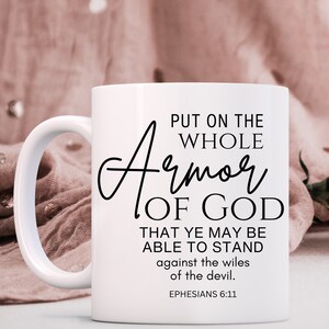 May include: White ceramic coffee mug with black text that reads "Put on the whole Armor of God that ye may be able to stand against the wiles of the devil. Ephesians 6:11"