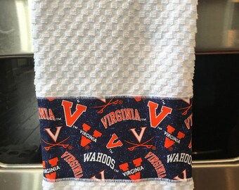 May include: White kitchen towel with a blue and orange border featuring the University of Virginia logo and the words "Virginia" and "Wahoos".