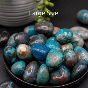 May include: A collection of large, tumbled blue and brown chrysocolla stones in a black bowl. The stones have a variety of patterns and textures. The text "Large Size" is visible in the image.