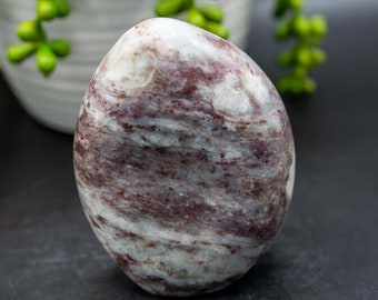 May include: A smooth, polished, oval-shaped stone with swirling patterns of white and deep red.