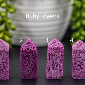 May include: Four pink ruby towers, labeled 1 through 4, on a black surface. The towers are all different shapes and sizes, but they are all made of the same type of ruby.