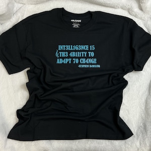 May include: Black t-shirt with a blue quote that reads "Intelligence is the ability to adapt to change - Stephen Hawking".